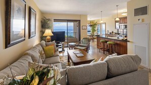 A living room with a sofa, a coffee table, and a TV. There is a balcony with a view of the ocean. - Ocean Views from the Top Floor - Kaanapali Alii 4112 (Lahaina)