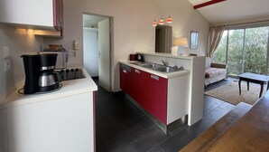 Een kleine keuken met een koffiezetapparaat, een gootsteen en een zithoek met een tafel en een bank.