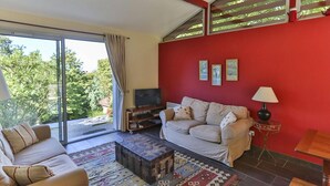 Een woonkamer met een rode wand, een bank, een salontafel en een televisie.