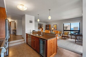 A modern kitchen with a central island, built-in appliances, and a dining area with a view. - Ocean Views & Indoor-Outdoor Living at Kaanapali Alii (Lahaina)