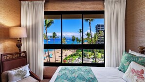 Ein Hotelzimmer mit großem Fenster und Blick auf Strand und Palmen.