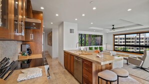 Une cuisine moderne avec des meubles en bois, un plan de travail en marbre et une grande fenêtre donnant sur la ville.