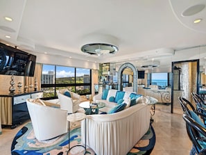 A spacious living room with a large white sofa, a round coffee table, and a view of the sea through large windows. - Dive Into Oceanfront Living | Resort Amenities at Kaanapali Alii (Lahaina)