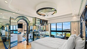 Una lujosa habitación de hotel con una cama grande, un balcón con vistas al océano y un diseño interior moderno.