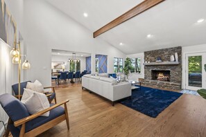 A spacious living area with a fireplace, a dining area, and a seating area with a blue rug. - Asheville Mtn Chalet: Spa & Theater (Asheville)
