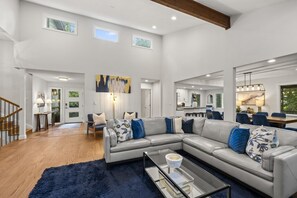 A spacious living room with a sectional sofa, a glass coffee table, and a dark blue rug. - Asheville Mtn Chalet: Spa & Theater (Asheville)