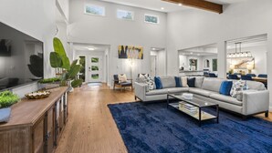 En moderne stue med sofa, sofabord og en stor plante.