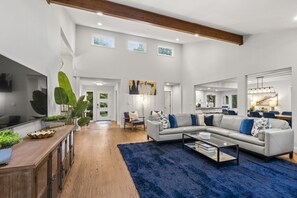 A modern living room with a sofa, coffee table, and a large plant. - Asheville Mtn Chalet: Spa & Theater (Asheville)