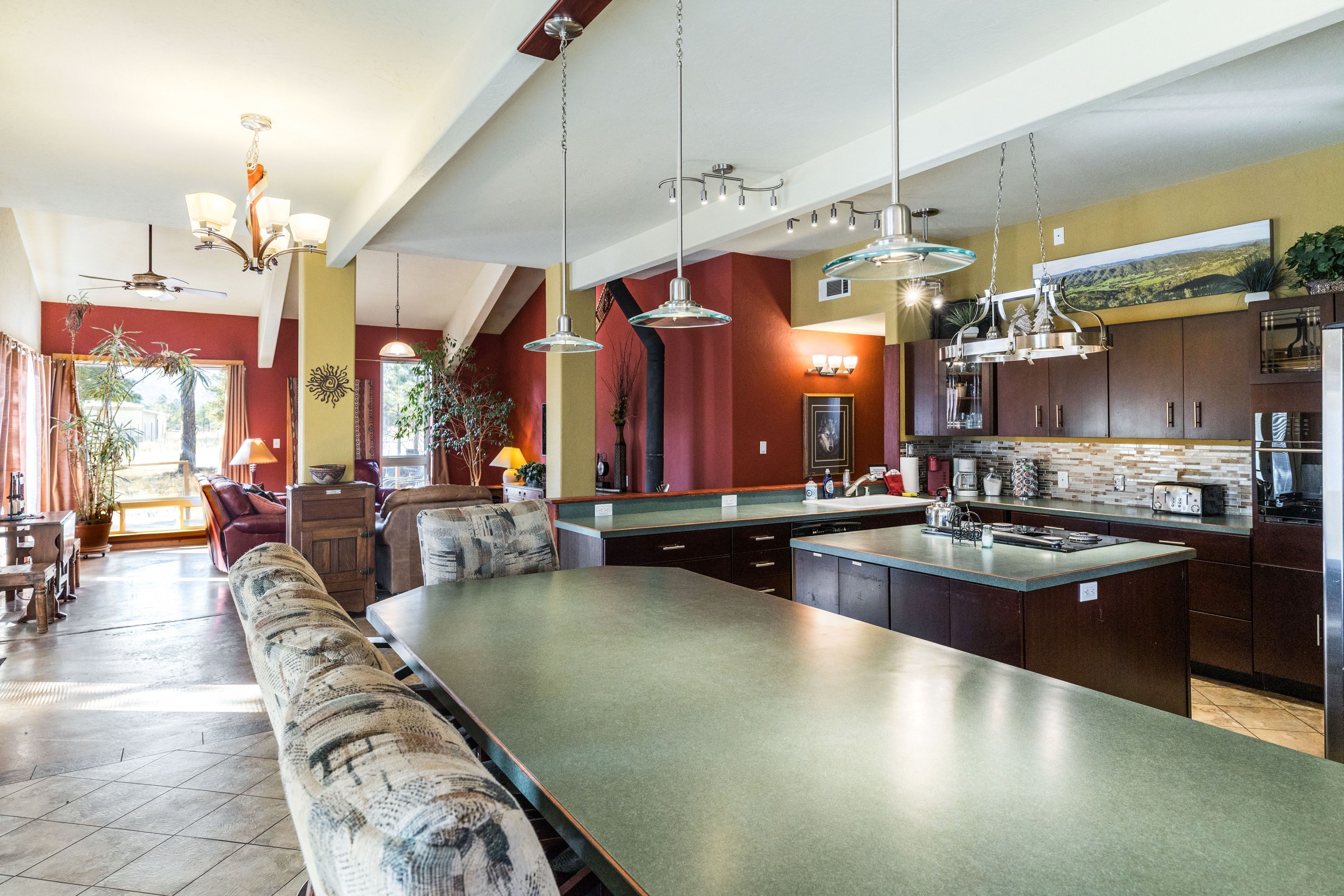 Une cuisine spacieuse dotée d’un grand îlot central, d’un éclairage moderne suspendu et offrant une vue sur l’extérieur.