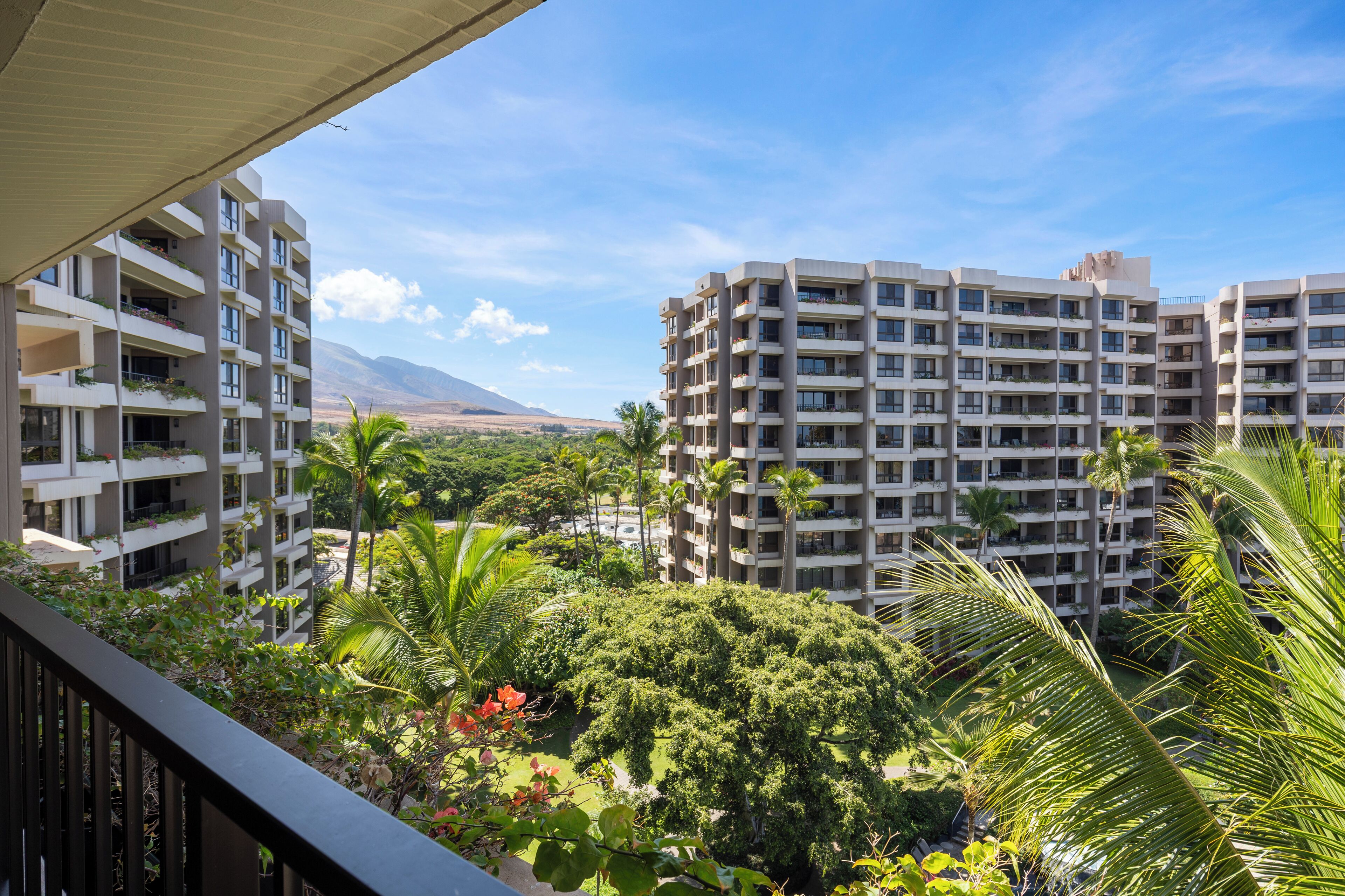 Un hôtel de grande hauteur doté de nombreux balcons, d’une végétation luxuriante et surplombant un paysage montagneux.