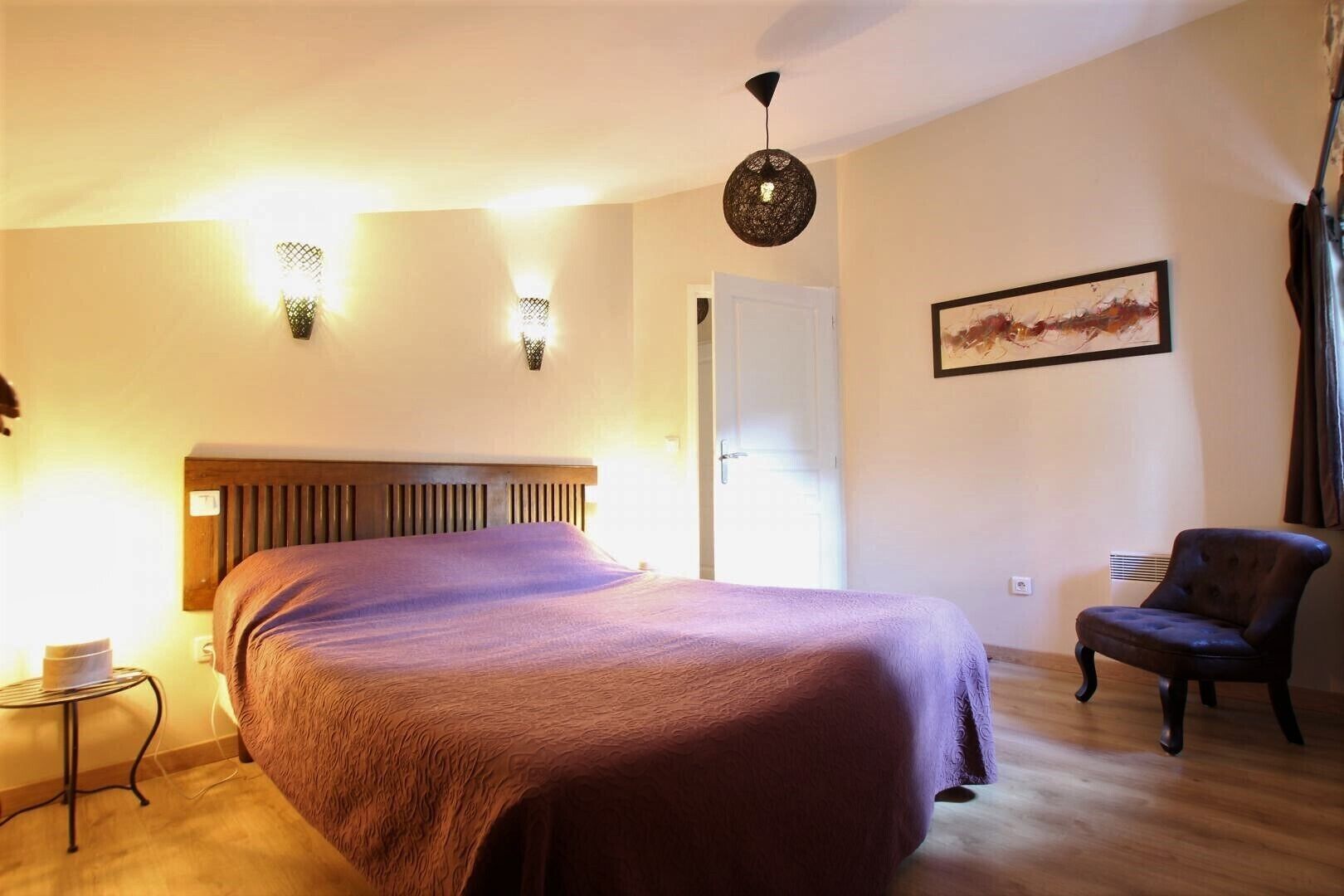 A bedroom with a bed, a chair, a radiator, and a door.