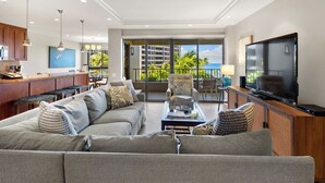 Ett modernt vardagsrum med en stor soffa, en tv och en balkong med utsikt över havet.