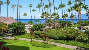 Un resort con área de piscina, palmeras y vista al océano.