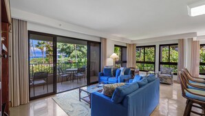 Amplia sala de estar con un sofá azul, una mesa de centro y vistas a un balcón con mobiliario exterior.