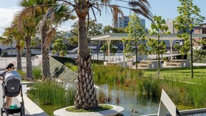 A landscaped area with a water feature, palm trees, and a covered seating area. - Stylish Inner-City Terrace Near Green Square (Zetland)