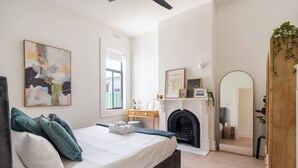 A bedroom with a bed, a fireplace, a mirror, and a window. - Stylish Inner-City Terrace Near Green Square (Zetland)