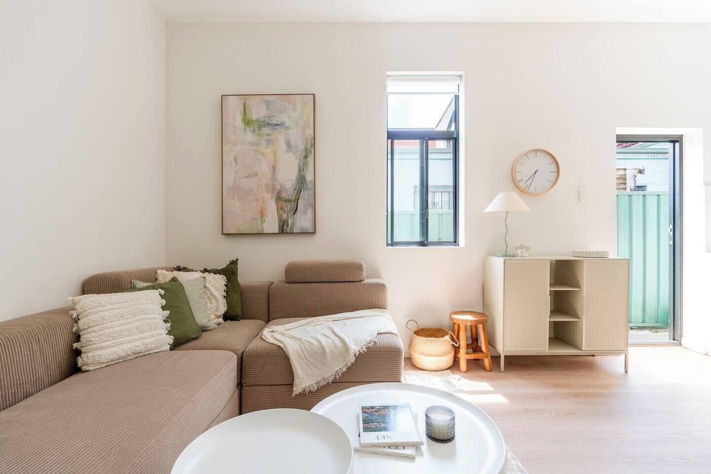 A living room with a sofa, a coffee table, a bookshelf, and a painting on the wall.