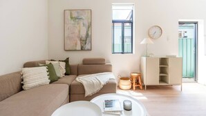 A living room with a sofa, a coffee table, a bookshelf, and a painting on the wall. - Stylish Inner-City Terrace Near Green Square (Zetland)