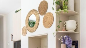 A room with a wooden dining table, white shelves with wicker baskets, a television, and decorative items including woven mirrors and plants. - Stylish Inner-City Terrace Near Green Square (Zetland)
