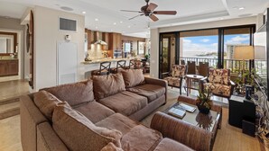 A spacious living area with a large sofa, a dining table, and a balcony with a view of the ocean. - Ocean Views & Resort Amenities at Kaanapali Alii w/ Private Lanai (Lahaina)