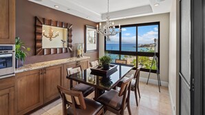 A modern kitchen with wooden cabinets, a granite countertop, and a dining area with a view of the ocean. - Ocean Views & Resort Amenities at Kaanapali Alii w/ Private Lanai (Lahaina)
