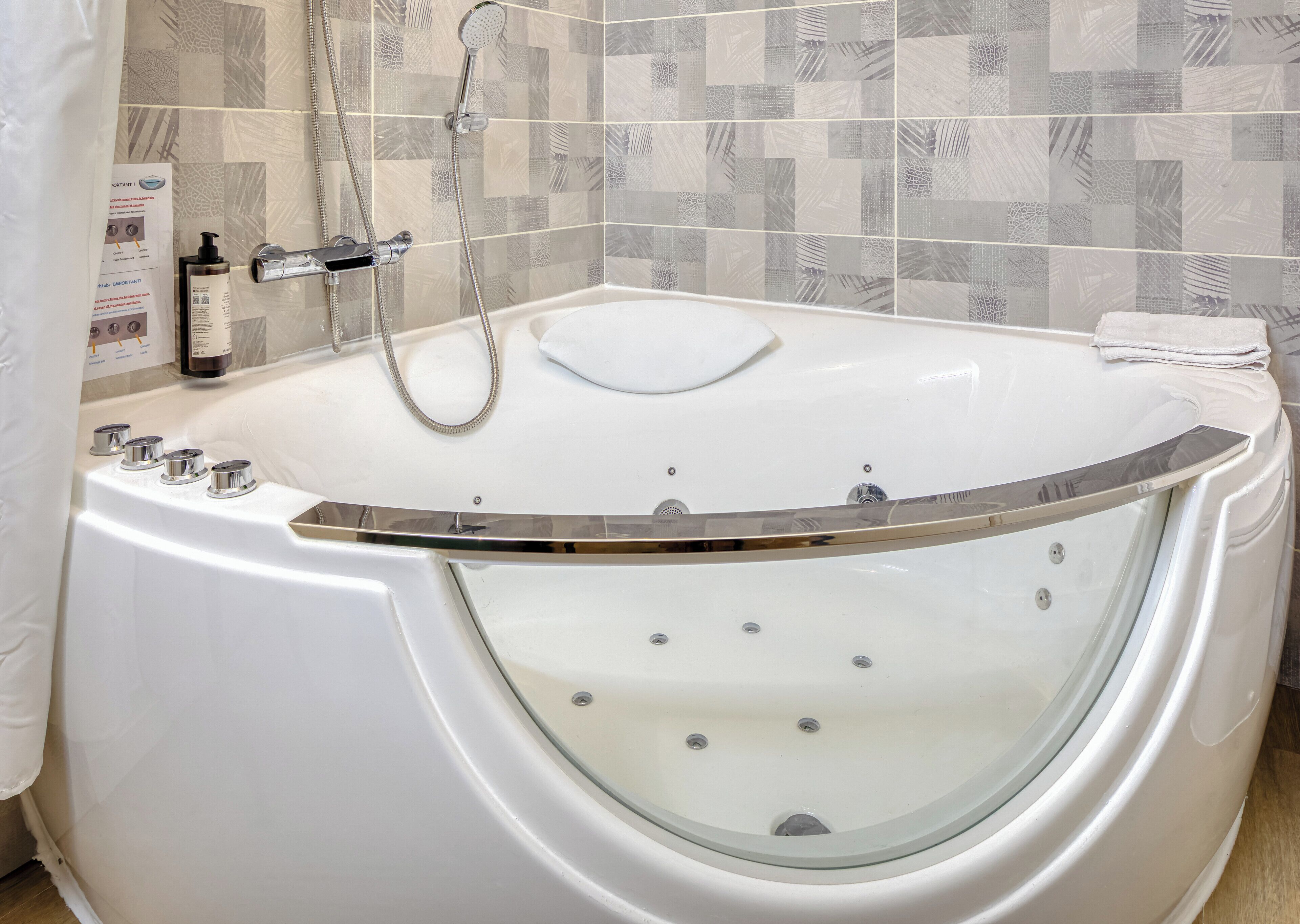 A modern bathroom with a freestanding bathtub, a handheld showerhead, and a glass-enclosed tub.