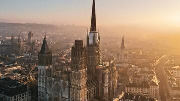 A cathedral with a tall spire, surrounded by historic buildings and a river.