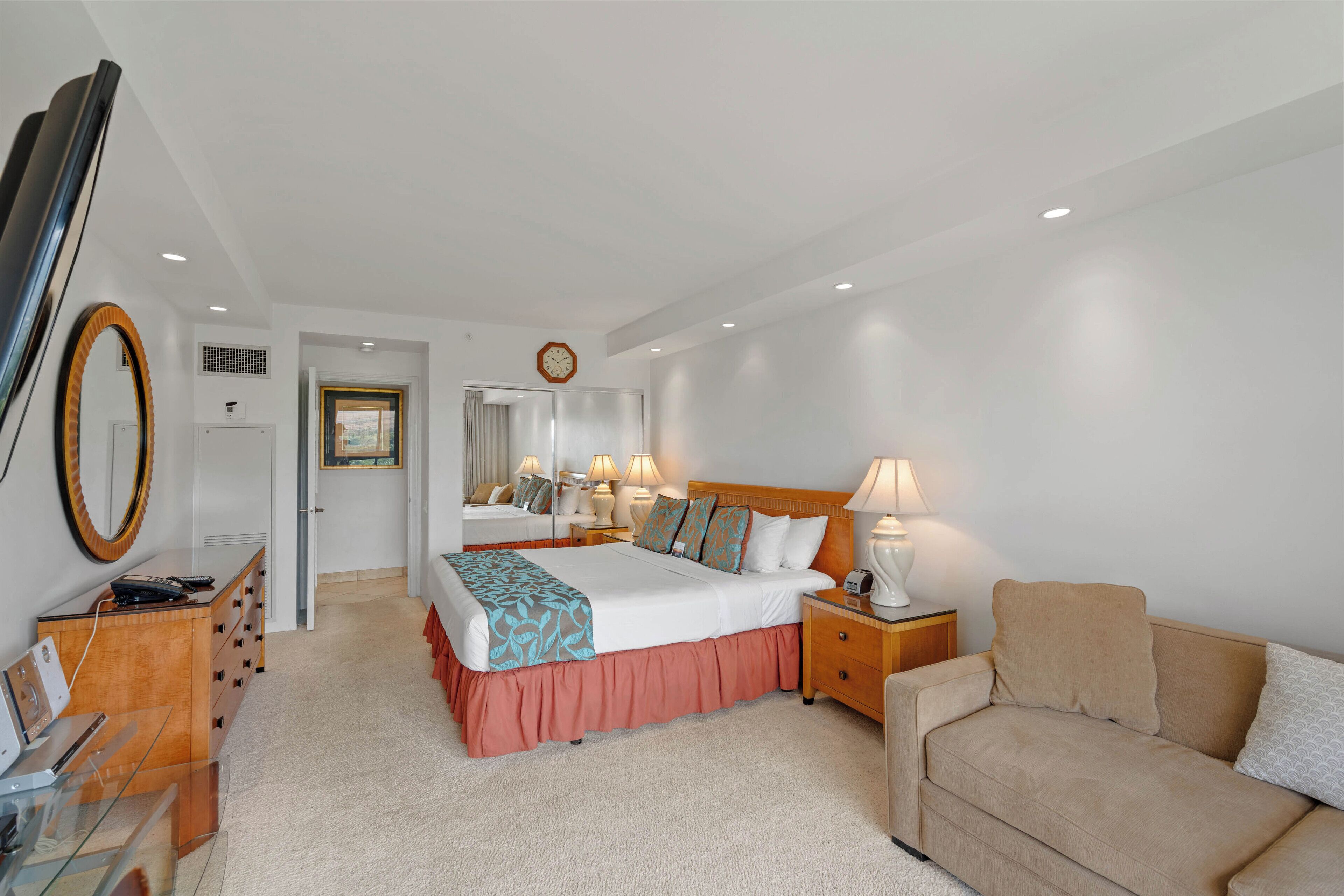 Une chambre d’hôtel avec un grand lit, un canapé, un bureau et un miroir.