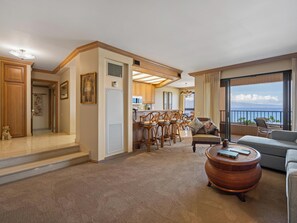 A spacious living area with a balcony, a kitchen, and a dining area. - Kaanapali Beach Ocean Views | Great for Families (Lahaina)
