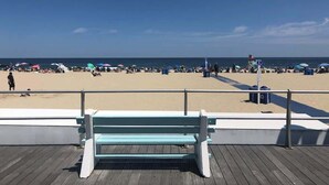 Une plage avec une terrasse en bois et un banc au premier plan.