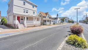 A two-story residential building with a front porch and a red door. - Wildwood Waves - 2BR Apt - Steps from Beach (Wildwood)