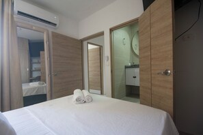 Een hotelkamer met een bed, een kledingkast, een badkamer met spiegel en een airconditioning.