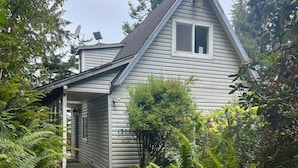 Ein bungalow mit überdachter Veranda, Satellitenschüssel und Briefkasten.
