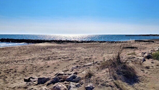 Een strand met een rotsachtige kustlijn en een heldere lucht.