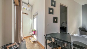 Een moderne eethoek met een lange tafel, stoelen, een potplant en een wandairconditioner.