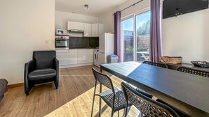 Een moderne keuken met witte kasten, een eethoek met een grote tafel en stoelen, en uitzicht op het groen buiten.