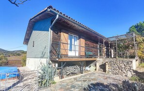 Ein Holzhaus mit Balkon, Stein Fundament und blauem Himmel.