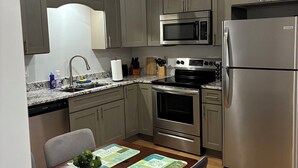 A modern kitchen with grey cabinets, stainless steel appliances, and a wooden dining table with placemats.