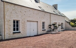 A large stone building with multiple garage doors, a sloped roof, and a gravel driveway.