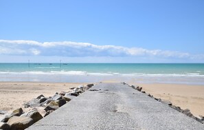 A concrete walkway leading to a beach with a clear sky and calm sea. - Maison cosy proche mer (Créances)