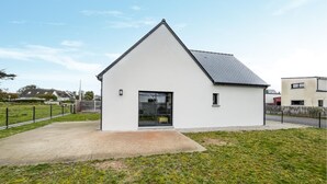 A small, modern white house with a sloped roof, a front door, and a small window. - Cozy home in Saint Germain sur Ay with WiFi (Saint Germain sur Ay)