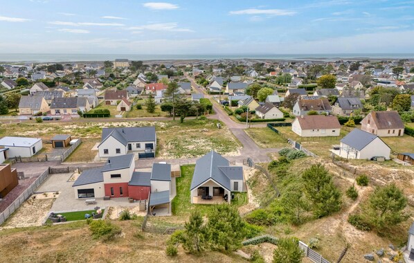 Área residencial com casas, algumas com garagens anexas, e vista desobstruída para o mar ao fundo.