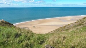 A coastal landscape with a sandy beach and grassy cliffs. - Cozy home in Saint Germain sur Ay with WiFi (Saint Germain sur Ay)