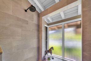 Ein Badezimmer mit Dusche, einem Fenster mit Milchglas und einer dekorativen Pferdestatue.