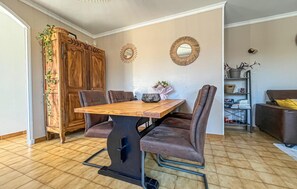 A dining area with a wooden table and cushioned chairs, a decorative mirror, and a bookshelf with various items. - Beautiful home in Cabannes (Cabannes)
