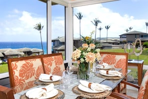 A dining table set for four with a view of the ocean and palm trees. - Kapalua Bay | Ocean View 6 BR, Sleeps 20 | Car Incl. w/ 6+ Nights | KBV ML-2056 by KBM (Lahaina)