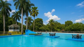 A swimming pool with a slide, lounge chairs, and a gazebo. - Ecohotel El Castillo Pance (Cali)