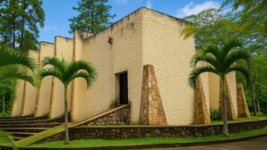A building with a stone facade, a set of stairs leading to a door, and palm trees in the foreground. - Ecohotel El Castillo Pance (Cali)