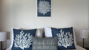 A bed with four pillows, two with a coral tree design and one with text. - Private pool and private beach in this wonderful Warwick beachfront apartment (Warwick Parish)