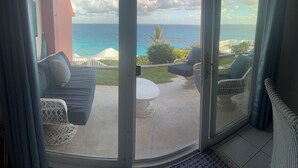A balcony with a view of the ocean, a white chair, a sofa, and a small table. - Private pool and private beach in this wonderful Warwick beachfront apartment (Warwick Parish)